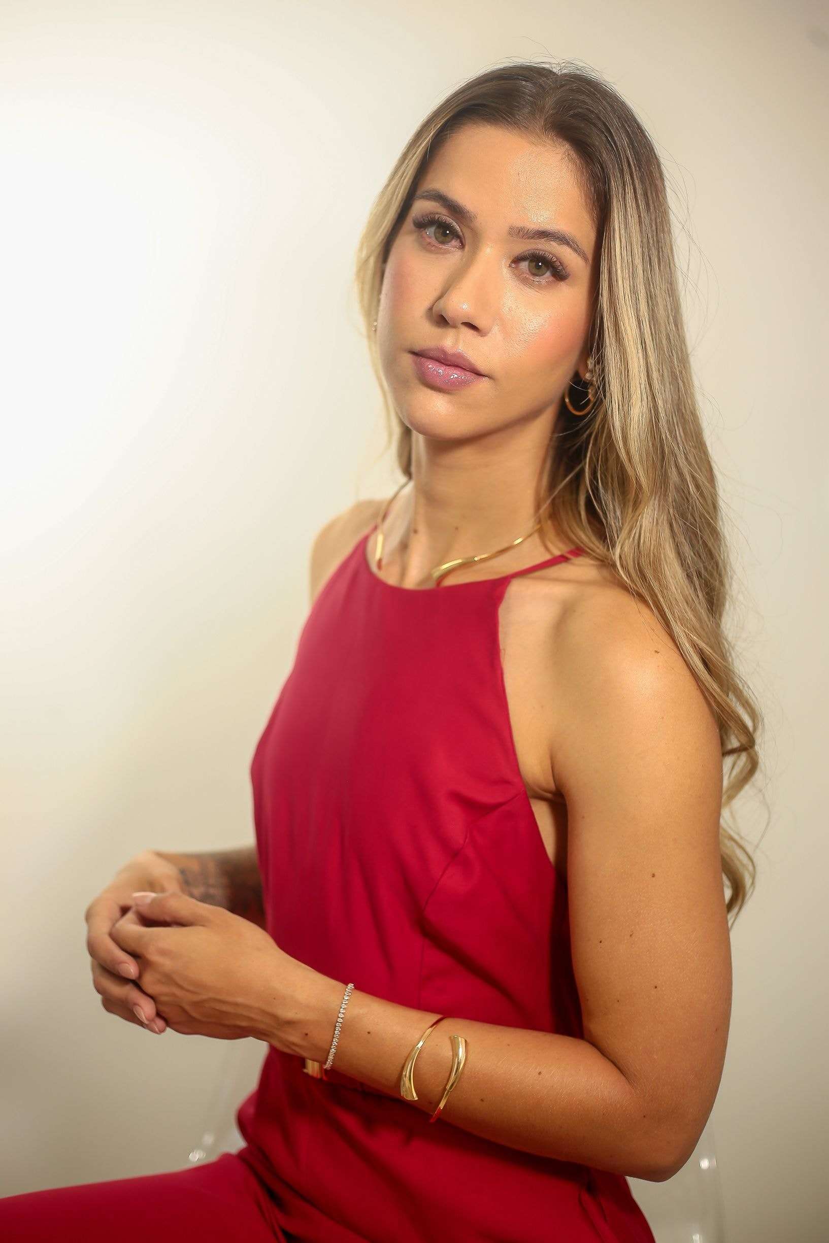 Dra. Alice Fortes de vestido vermelho, sentada, com as mãos unidas.